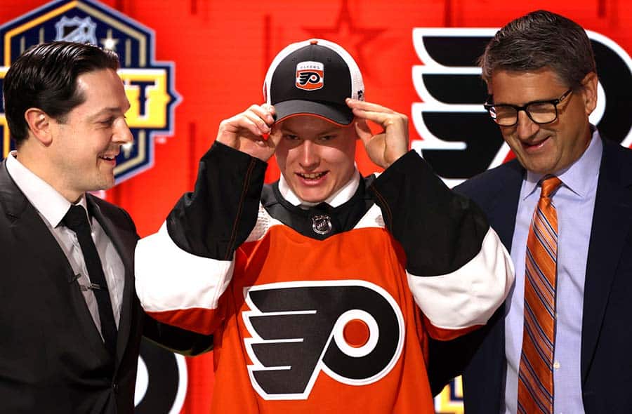 Matvei Michkov stands onstage with general manager Daniel Briere and Keith Jones after being selected seventh overall by the Philadelphia Flyers the 2023 Upper Deck NHL Draft - Round One at Bridgestone Arena on June 28, 2023 in Nashville, Tennessee.